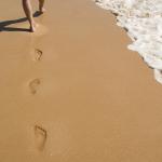 Des empreintes de pieds dans le sable mouillé par la mer